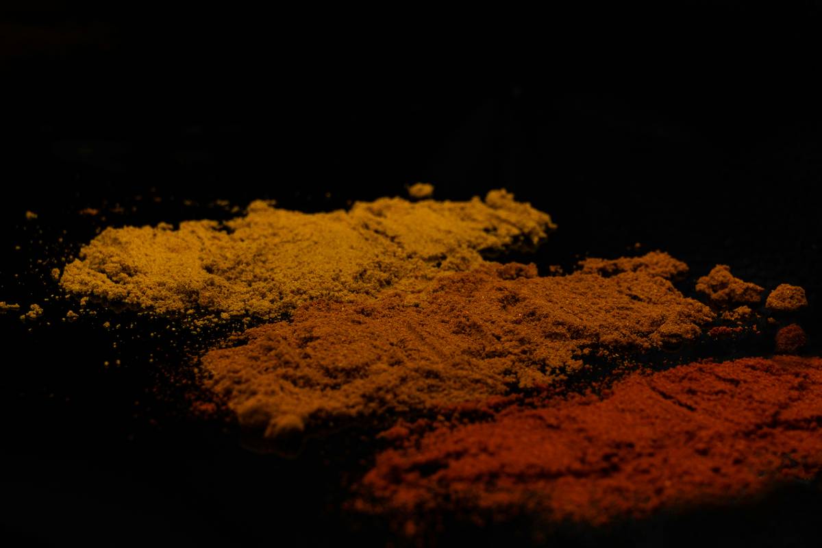 A spoonful of bright yellow turmeric powder on a wooden table